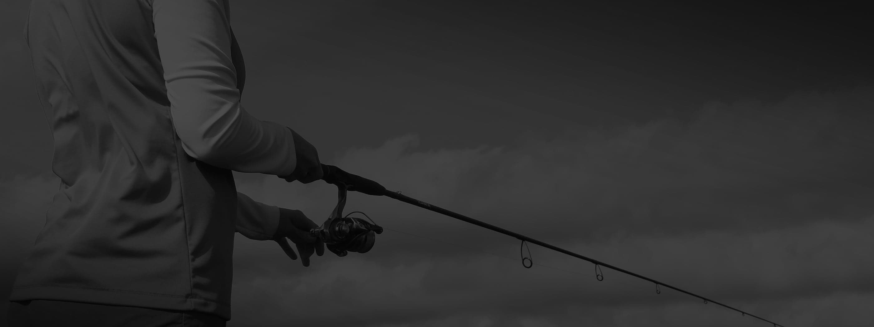 Close up of an angler reeling in a fish using a Trika fishing rod standing up on a boat
